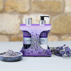 Cotswold Lavender body wash and lotion set with lavender flowers on a stone surface.