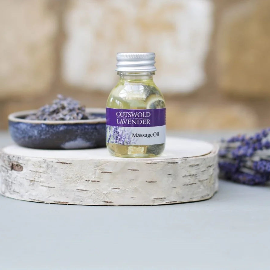Bottle of Cornwood Lavender Massage Oil on a wooden tray with lavender flowers.