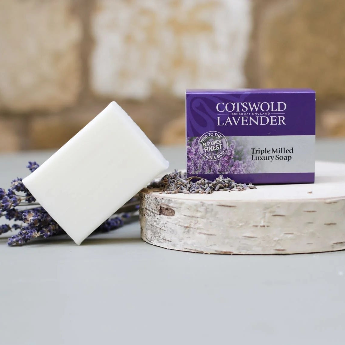 Cotswold Lavender soap bar and packaging on a wooden block with lavender flowers.